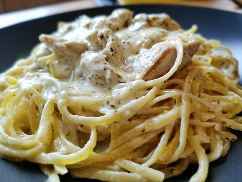 A close-up shot of delicious Creamy Alfredo Chicken Pasta featuring linguine coated in rich white sauce and topped with seasoned chicken pieces.