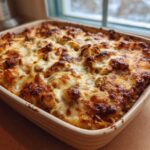 A freshly baked casserole dish filled with Creamy Cajun Chicken Alfredo Bake, featuring a golden, bubbly, and browned cheese topping.