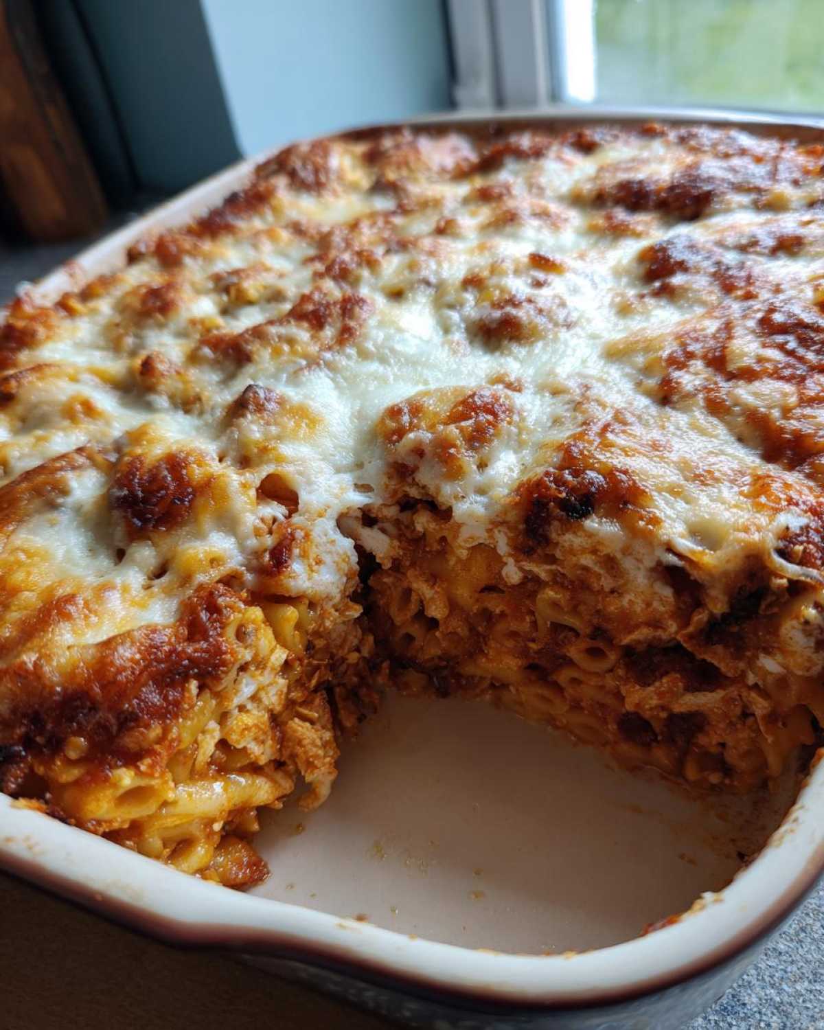 A portion removed from a Creamy Cajun Chicken Alfredo Bake showing the cheesy, baked pasta layers.