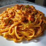 Close-up of fettuccine noodles coated in a rich, orange sauce with chunks of chicken and green peppers in Creamy Cajun Chicken Pasta.