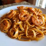 A close-up of Creamy Cajun Shrimp Pasta featuring fettuccine coated in a rich sauce and topped with seasoned shrimp.