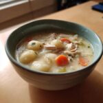Close-up of a bowl of rich Creamy Chicken Gnocchi Soup featuring soft gnocchi, shredded chicken, and bright orange carrot slices.