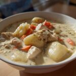 Close-up of a hearty bowl of Creamy Chicken Gnocchi Soup featuring chunks of chicken, soft potatoes, and bright orange carrots in a rich broth.