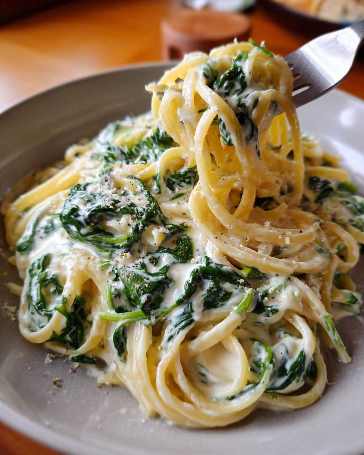A fork lifting a twirl of Creamy Lemon Ricotta Pasta with Spinach coated in a rich white sauce.