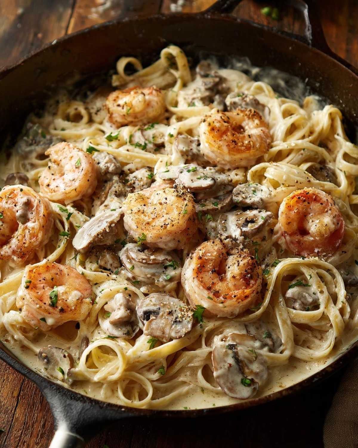 Close-up of Creamy Mushroom Alfredo Shrimp Skillet featuring fettuccine, sautéed mushrooms, and seasoned shrimp in a rich sauce.