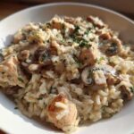 Close-up of a bowl filled with Creamy Mushroom Chicken and Rice Skillet, topped with parsley.