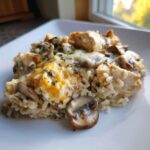 Close-up of a serving of Creamy Mushroom Chicken and Rice Skillet topped with melted cheese and herbs.