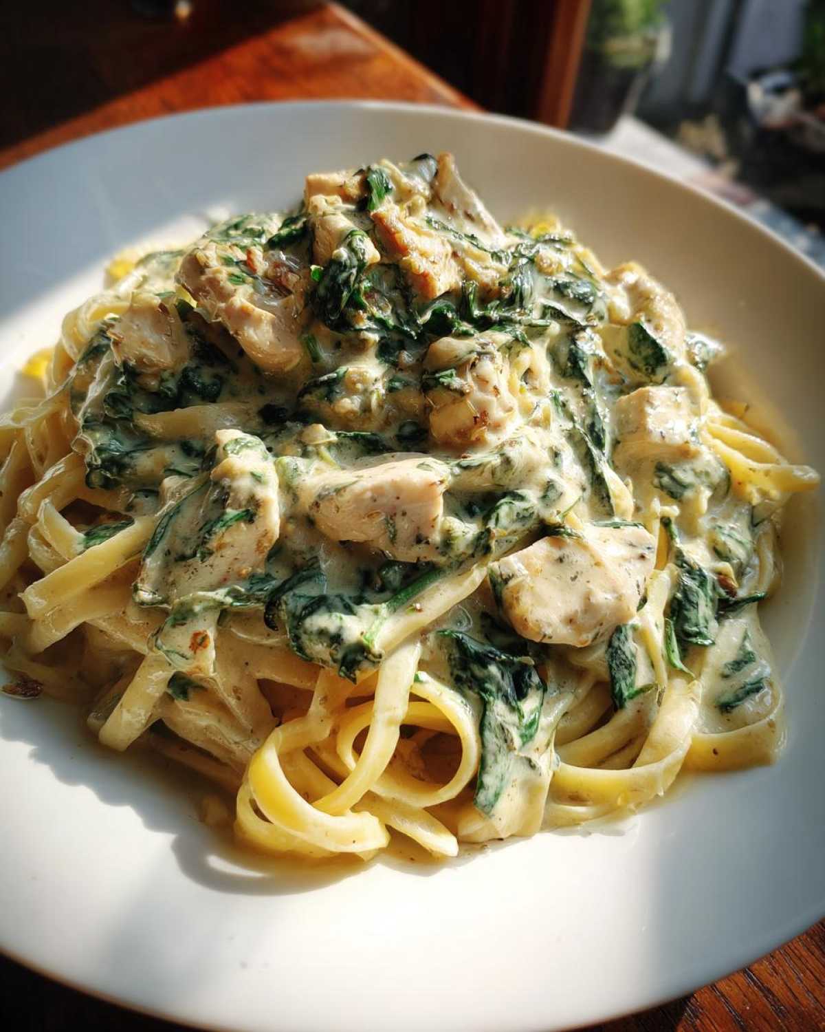 Close-up of fettuccine pasta tossed in a rich cream sauce with spinach and chunks of chicken, ready for a Creamy Spinach Pasta with Chicken Dinner.
