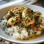 Close-up of Garlic Butter Chicken and Rice One Pot Dinner, featuring pieces of chicken in garlic butter sauce over white rice, topped with parsley.