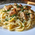 Close-up of a serving of Garlic Butter Chicken Pasta with Cream Sauce, topped with seasoned chicken pieces and fresh parsley.
