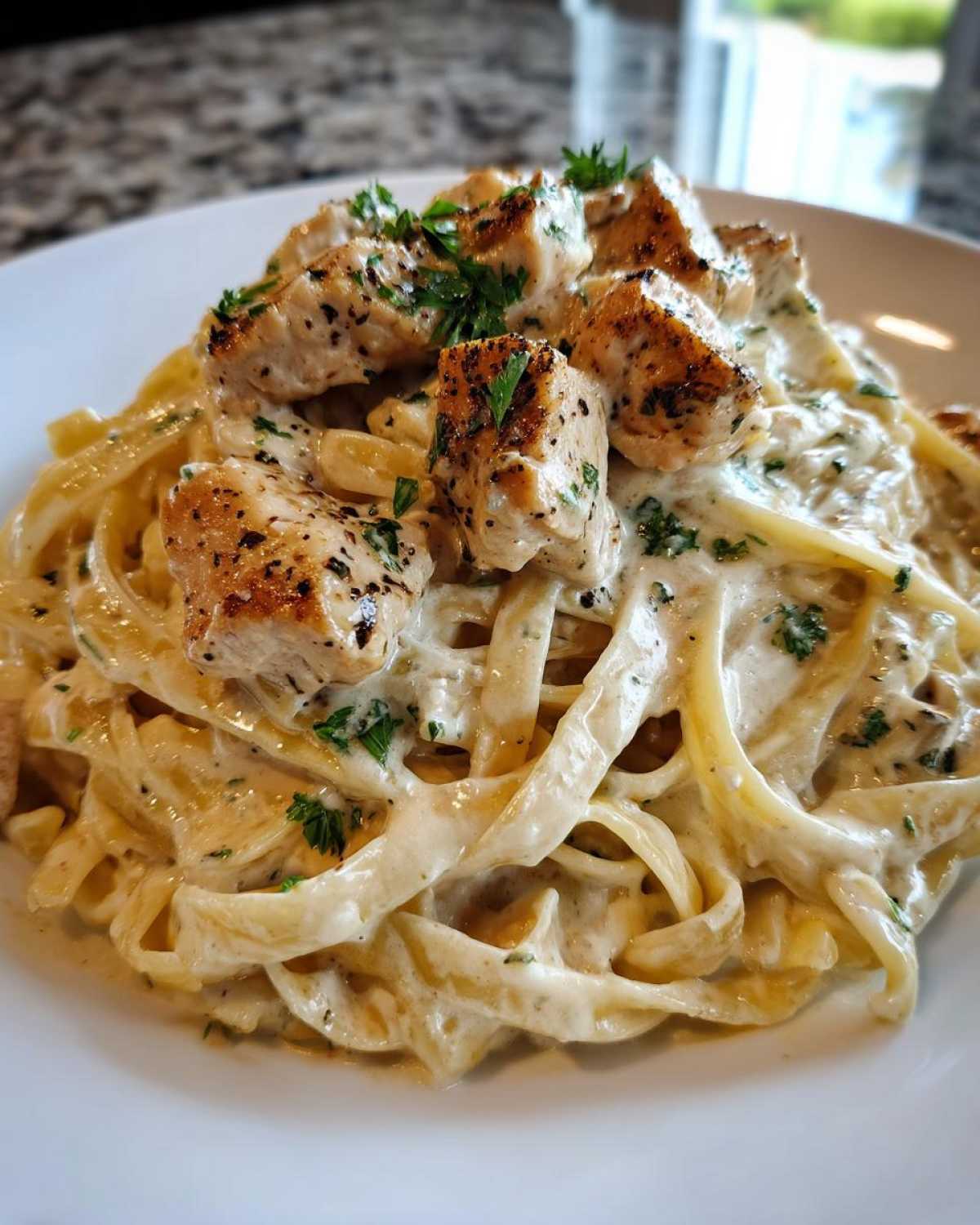 Close-up of Garlic Butter Chicken Pasta with fettuccine noodles coated in a rich cream sauce and topped with seasoned chicken pieces.