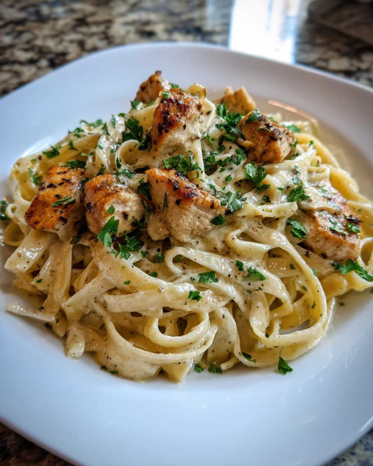 Close-up of Garlic Butter Chicken Pasta with cream sauce, featuring grilled chicken pieces and fresh parsley.