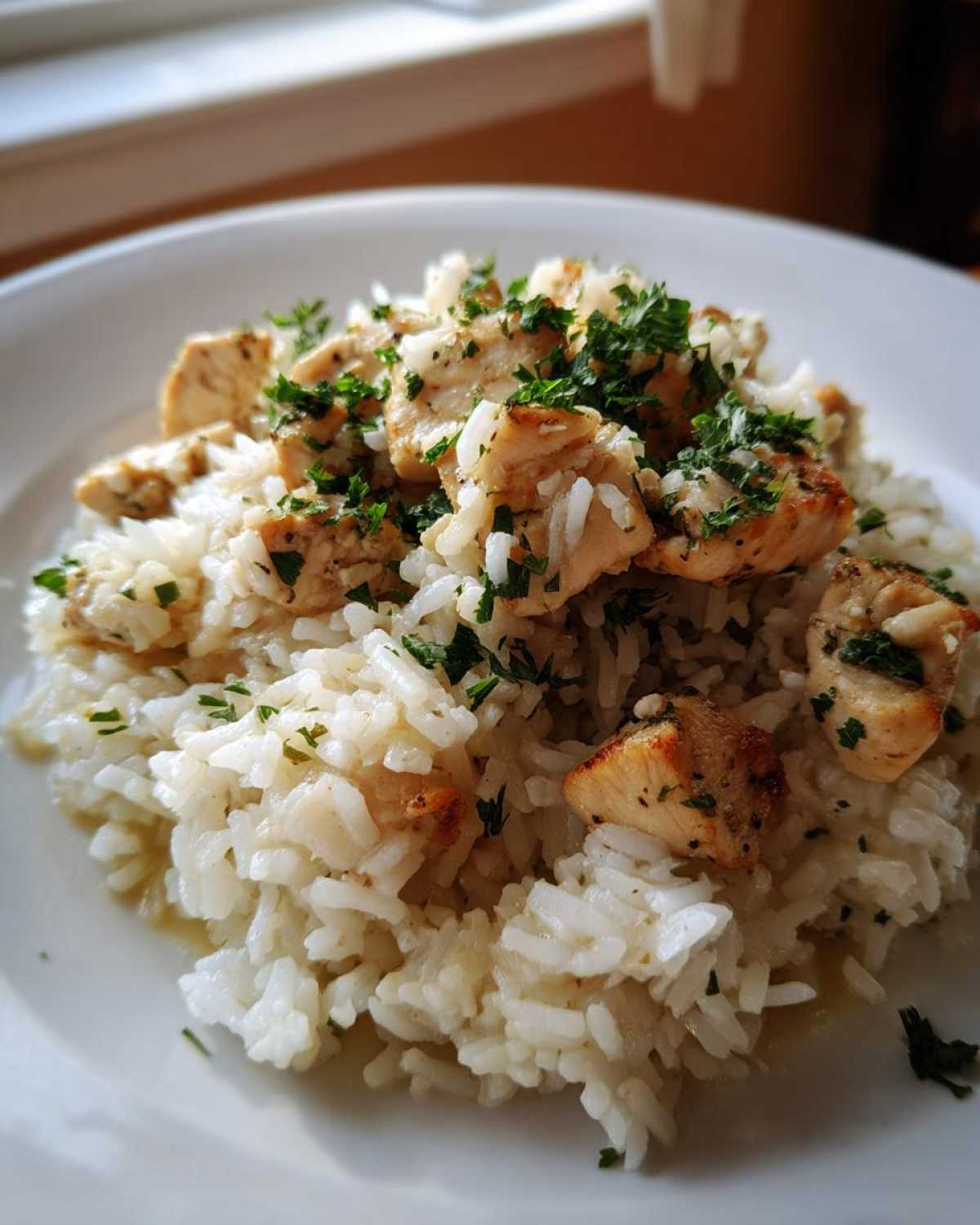 A close-up of Garlic Butter Rice with Chicken Skillet, featuring seasoned chicken pieces over buttery white rice, topped with fresh parsley.