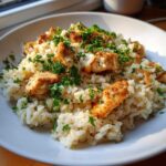 Close-up of a white bowl filled with Garlic Butter Rice with Chicken Skillet, topped with fresh parsley.