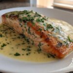 A perfectly cooked fillet of Garlic Butter Salmon with Creamy Lemon Sauce, topped with fresh parsley.