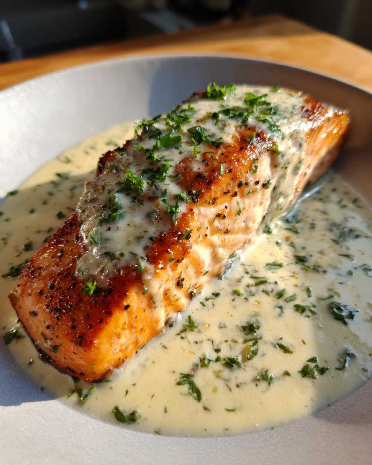 A perfectly seared fillet of Garlic Butter Salmon with Creamy Lemon Sauce, garnished with parsley.