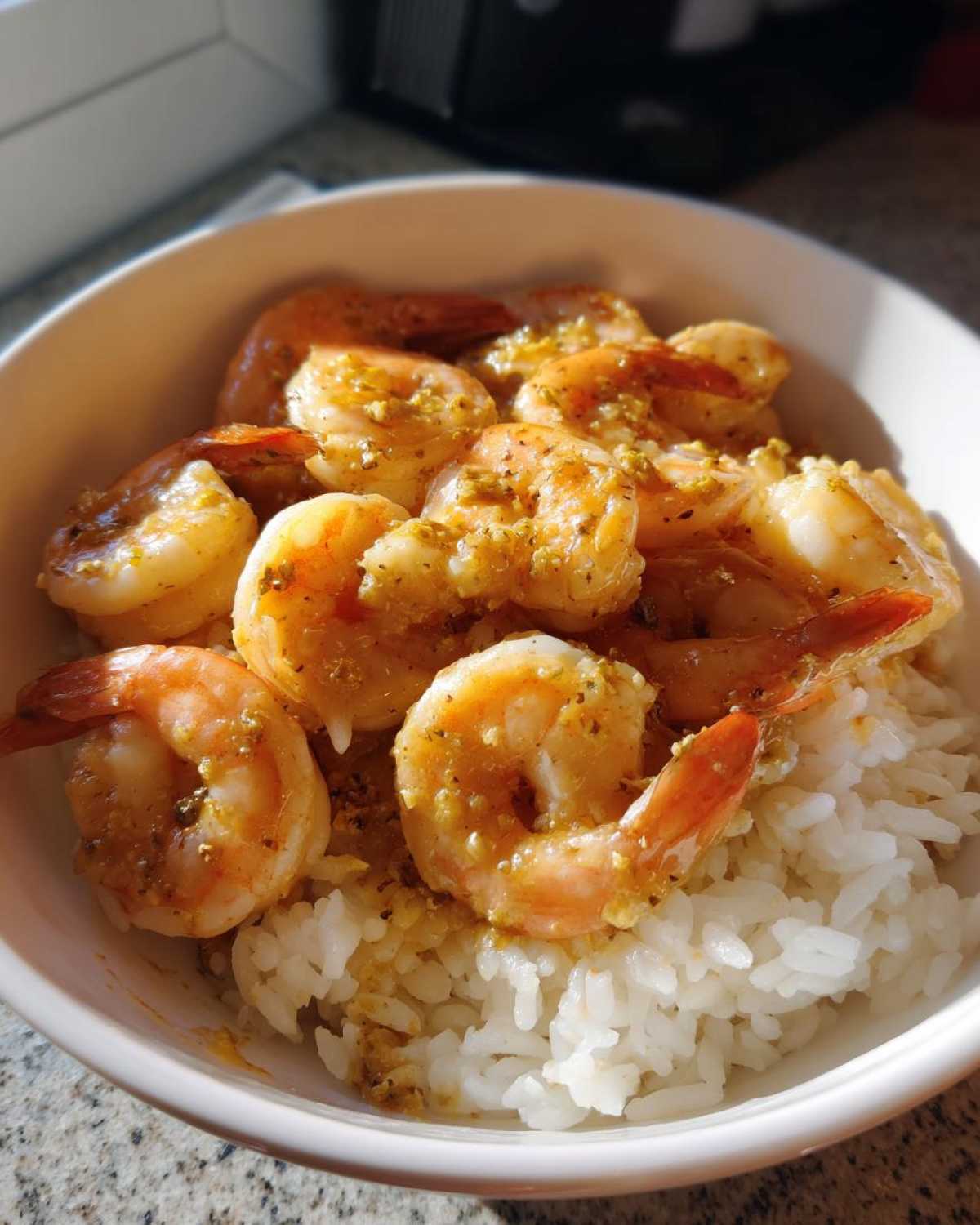 Close-up of a white bowl filled with fluffy white rice topped generously with succulent Garlic Butter Shrimp Bowl with Rice.