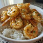 Close-up of a white bowl filled with white rice topped generously with juicy Garlic Butter Shrimp Bowl with Rice.