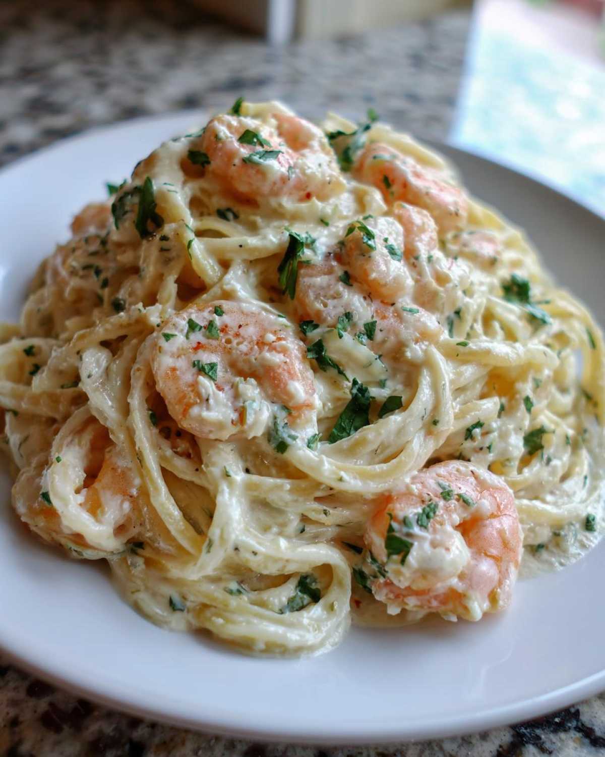 A close-up of creamy Garlic Butter Shrimp Pasta with Cream Sauce, garnished with fresh parsley, served on a white plate.