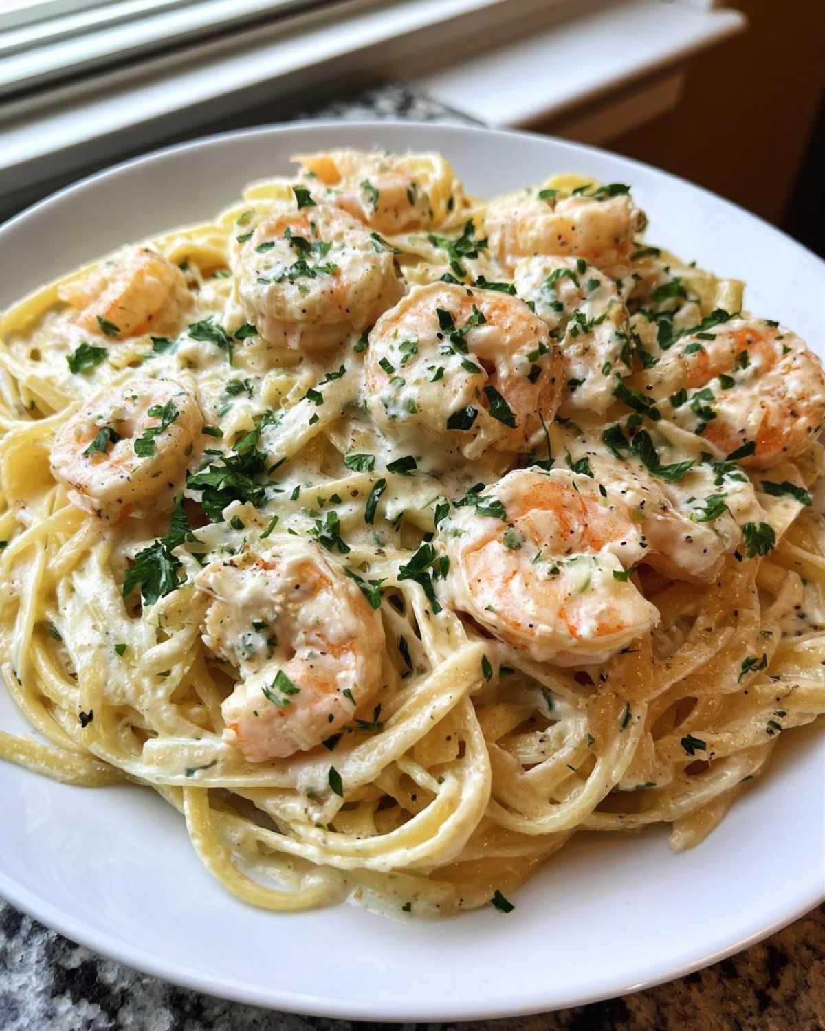 Close-up of Garlic Butter Shrimp Pasta with Cream Sauce, topped with fresh parsley.