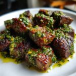 Close-up of seared Garlic Butter Steak Bites generously topped with a vibrant green herb sauce.