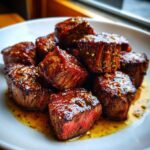 Close-up of perfectly seared Garlic Butter Steak Bites with a juicy, medium-rare center resting in butter sauce.