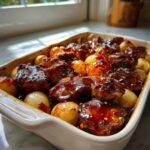 Close-up of Honey BBQ Chicken Bake with Potatoes, featuring glazed chicken pieces and small roasted potatoes in a white baking dish.