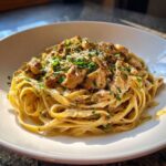 A bowl of Honey Garlic Chicken Pasta with Cream Sauce, topped with chopped parsley and Parmesan cheese.