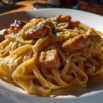 A close-up shot of creamy fettuccine pasta topped with glazed chicken pieces, representing Honey Garlic Chicken Pasta with Cream Sauce.