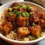 Close-up of Honey Garlic Chicken Skillet with Rice, featuring glazed chicken pieces over brown rice, topped with green onions.