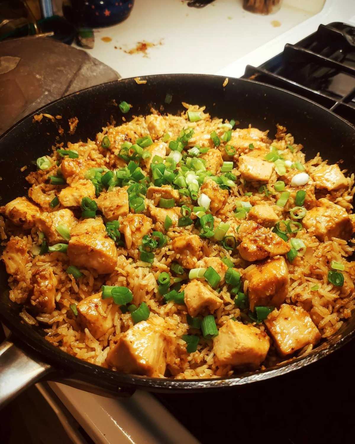 Close-up of Honey Garlic Chicken Skillet with Rice topped generously with sliced green onions.