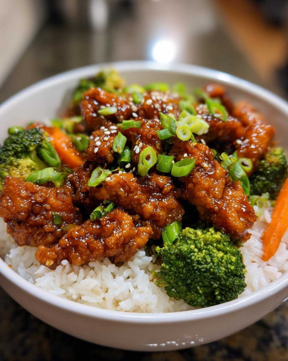 A close-up of a Honey Soy Chicken Bowl Quick Dinner Idea featuring glazed chicken pieces over white rice with broccoli and carrots.