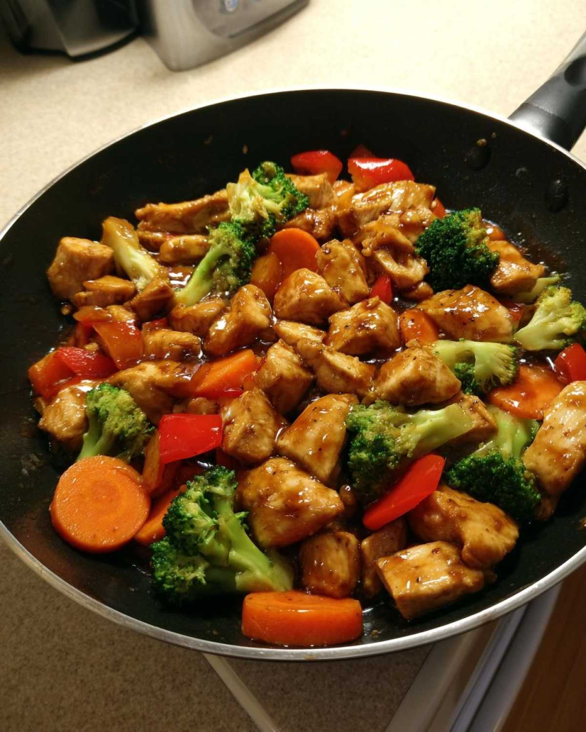 Close-up of Honey Soy Chicken Skillet with Veggies, featuring glazed chicken pieces, broccoli, carrots, and red peppers in a black skillet.