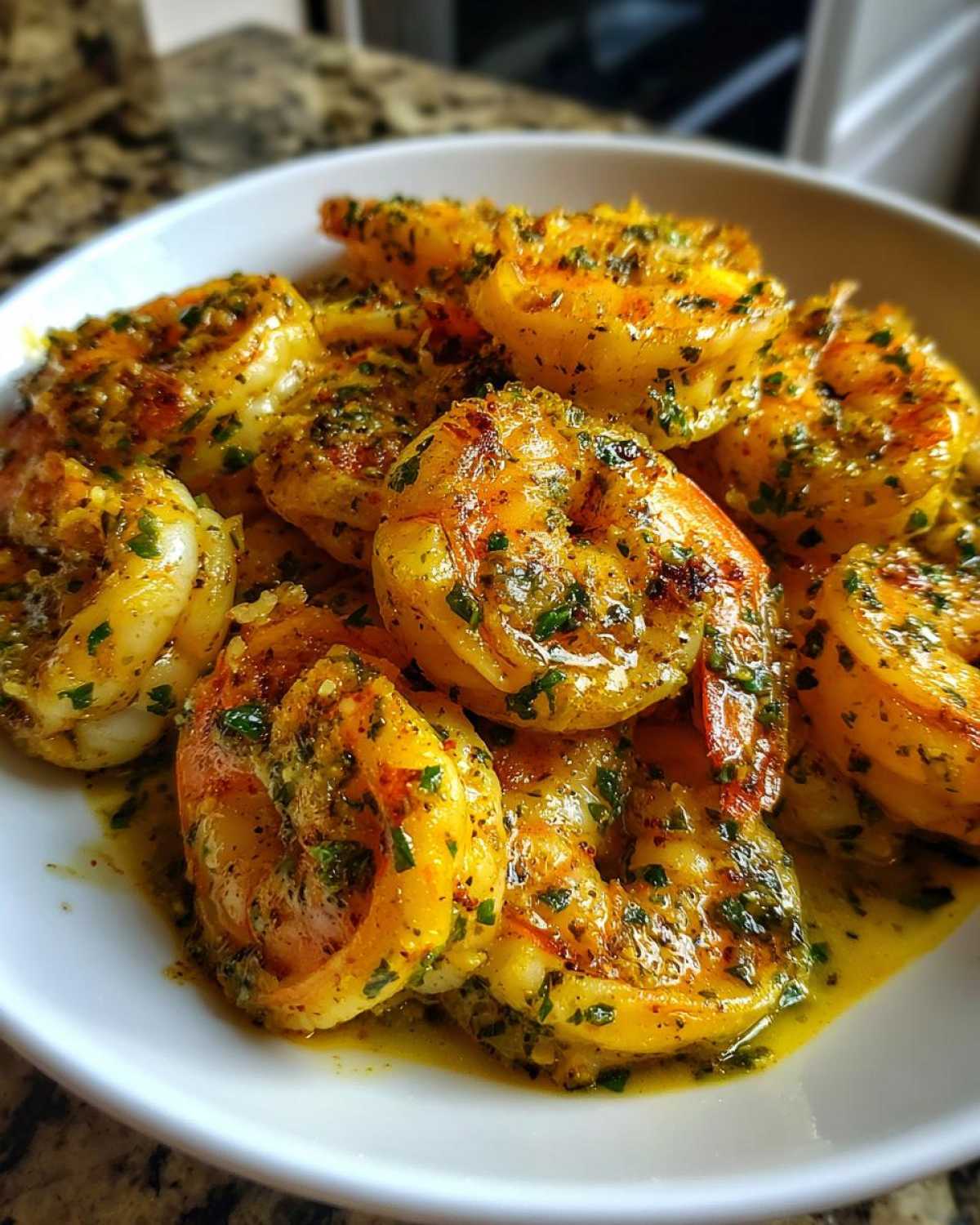 Close-up of succulent shrimp coated in a rich, yellow lemon butter sauce with visible garlic and chopped parsley, representing Lemon Butter Shrimp with Garlic Flavor.