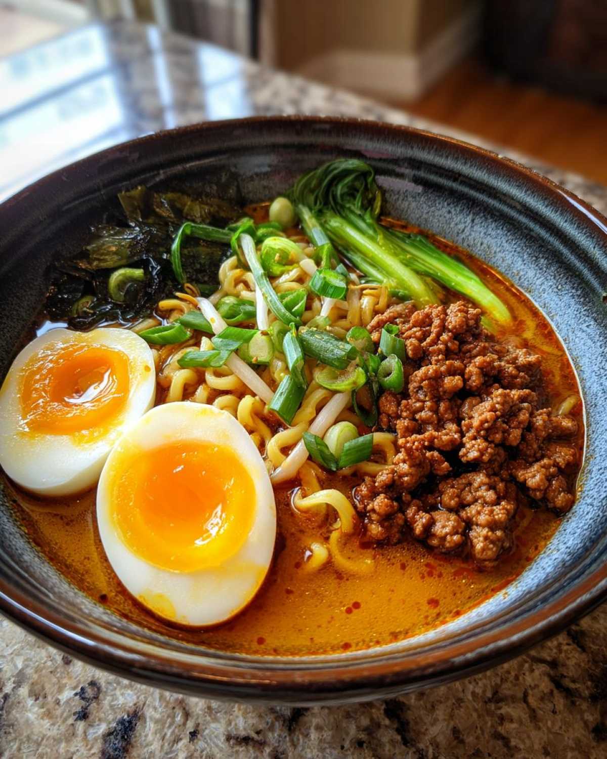 A close-up of Spicy Miso Ramen featuring rich broth, noodles, ground meat, and two halves of soft-boiled eggs.