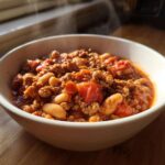 A steaming white bowl filled with rich, thick Spicy Turkey White Bean Chili featuring ground turkey and white beans.