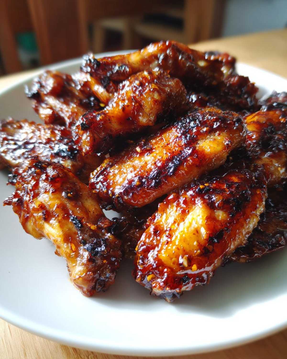 A pile of perfectly glazed, caramelized Sticky Honey Garlic Wings Oven Baked served on a white plate.