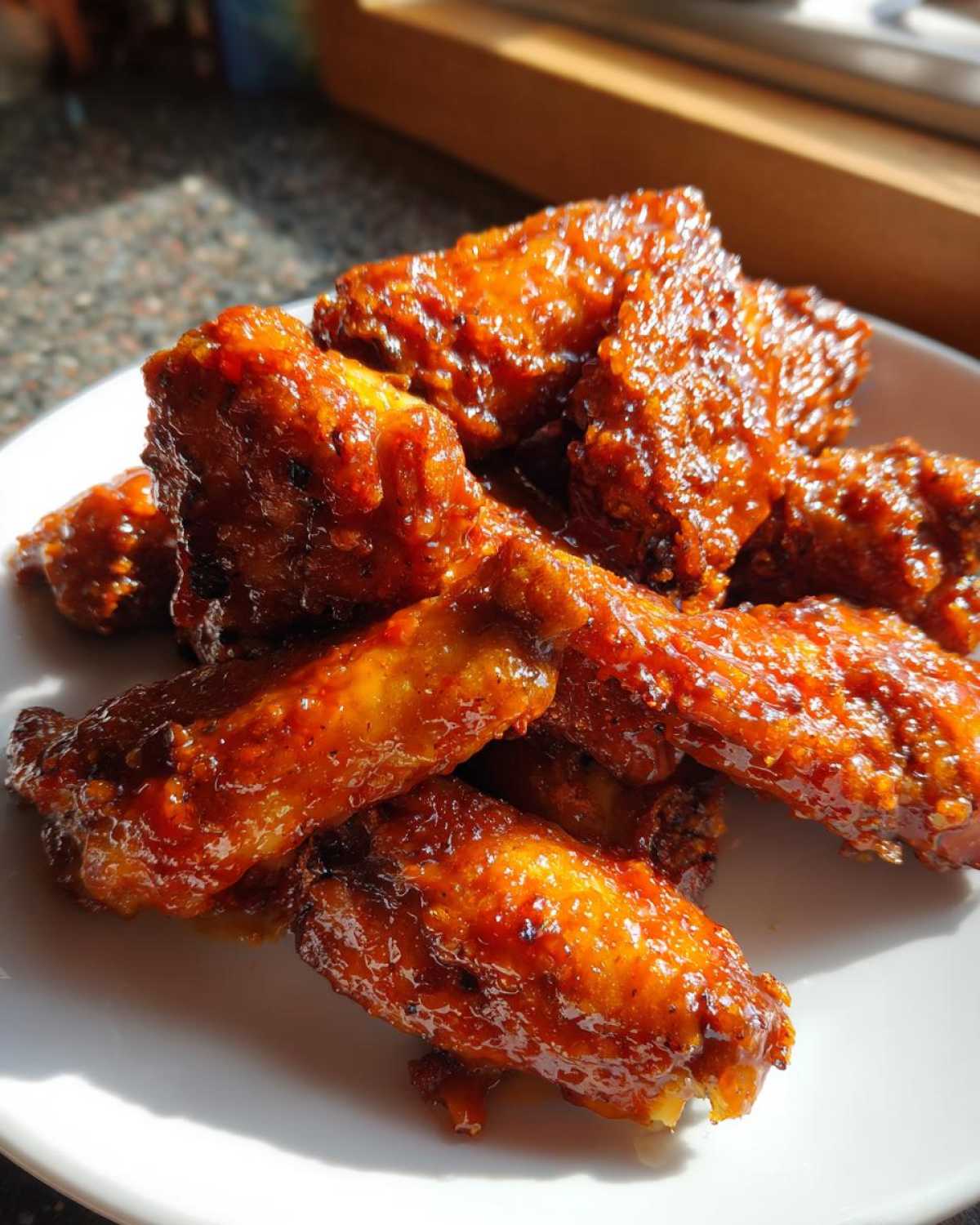 A pile of glistening, saucy Sticky Orange Chicken Thighs Better Than Takeout served on a white plate.