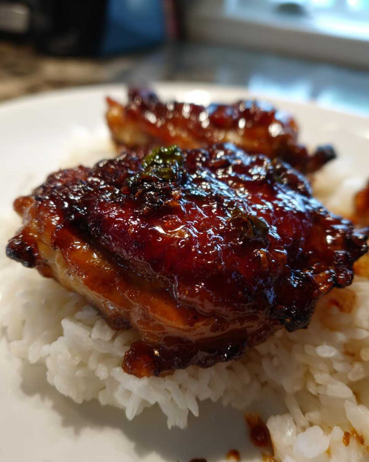 Close-up of Sticky Sweet Chili Chicken Thighs with a glossy glaze served over white rice on a plate.