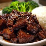 Close-up of Sticky Teriyaki Chicken Easy coated in a dark glaze, served with white rice and steamed broccoli florets.