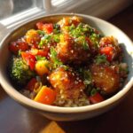 Close-up of a Sweet Chili Chicken Bowl with crunchy veggies, brown rice, and sesame seeds.