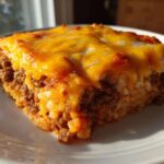 A close-up serving of Cheesy Beef and Rice Casserole Comfort Dish topped with melted cheddar cheese.