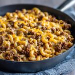 Melted cheddar cheese topping a Cheesy Ground Beef Pasta Skillet Comfort Food made with elbow macaroni and seasoned ground beef.