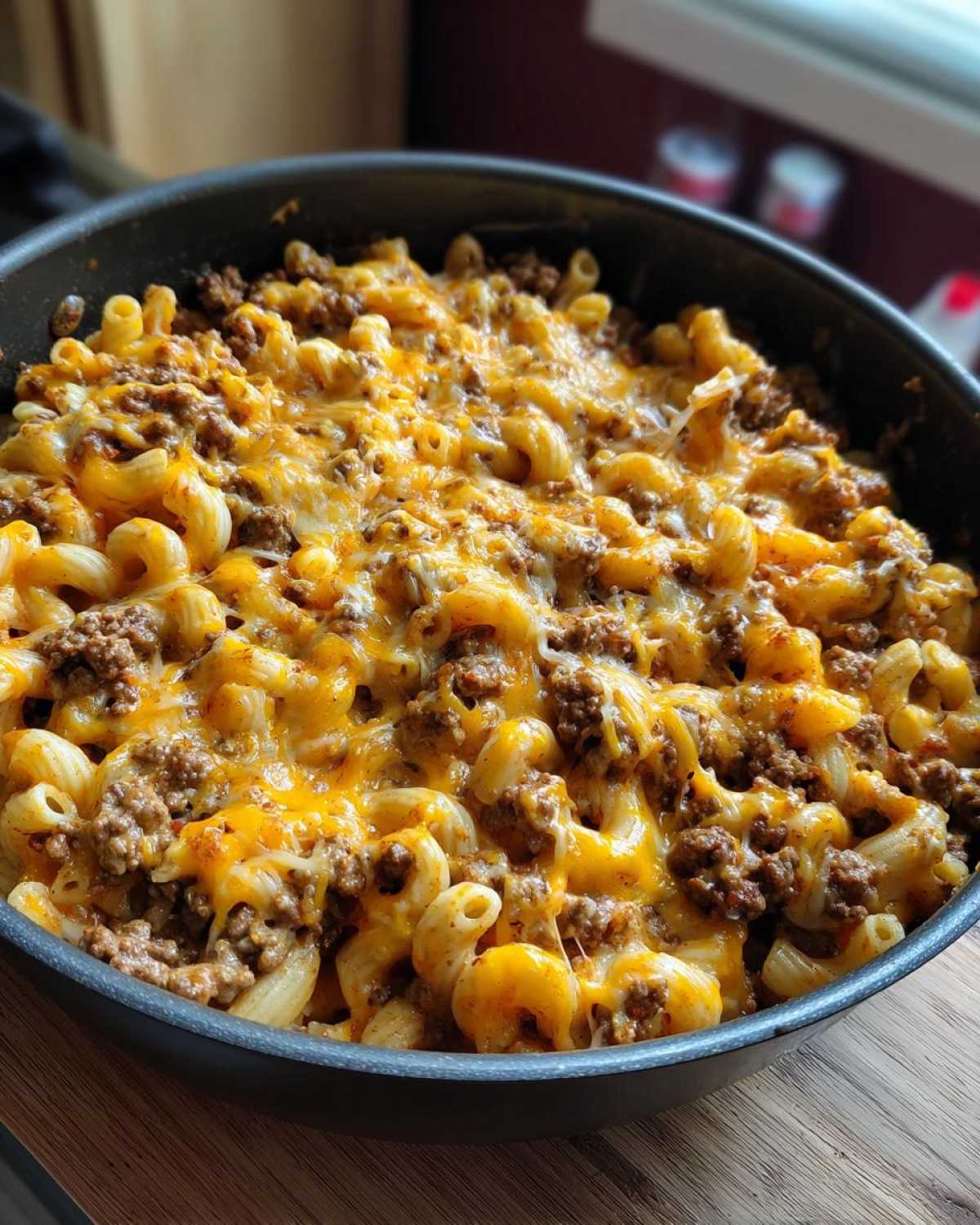 Close-up of a skillet filled with Cheesy Ground Beef Pasta Skillet Comfort Food, topped with melted cheddar cheese.