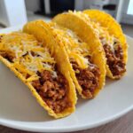 Three crispy hard-shell tacos filled with seasoned ground beef and topped generously with shredded cheddar and Monterey Jack cheese, perfect Cheesy Ground Beef Tacos.