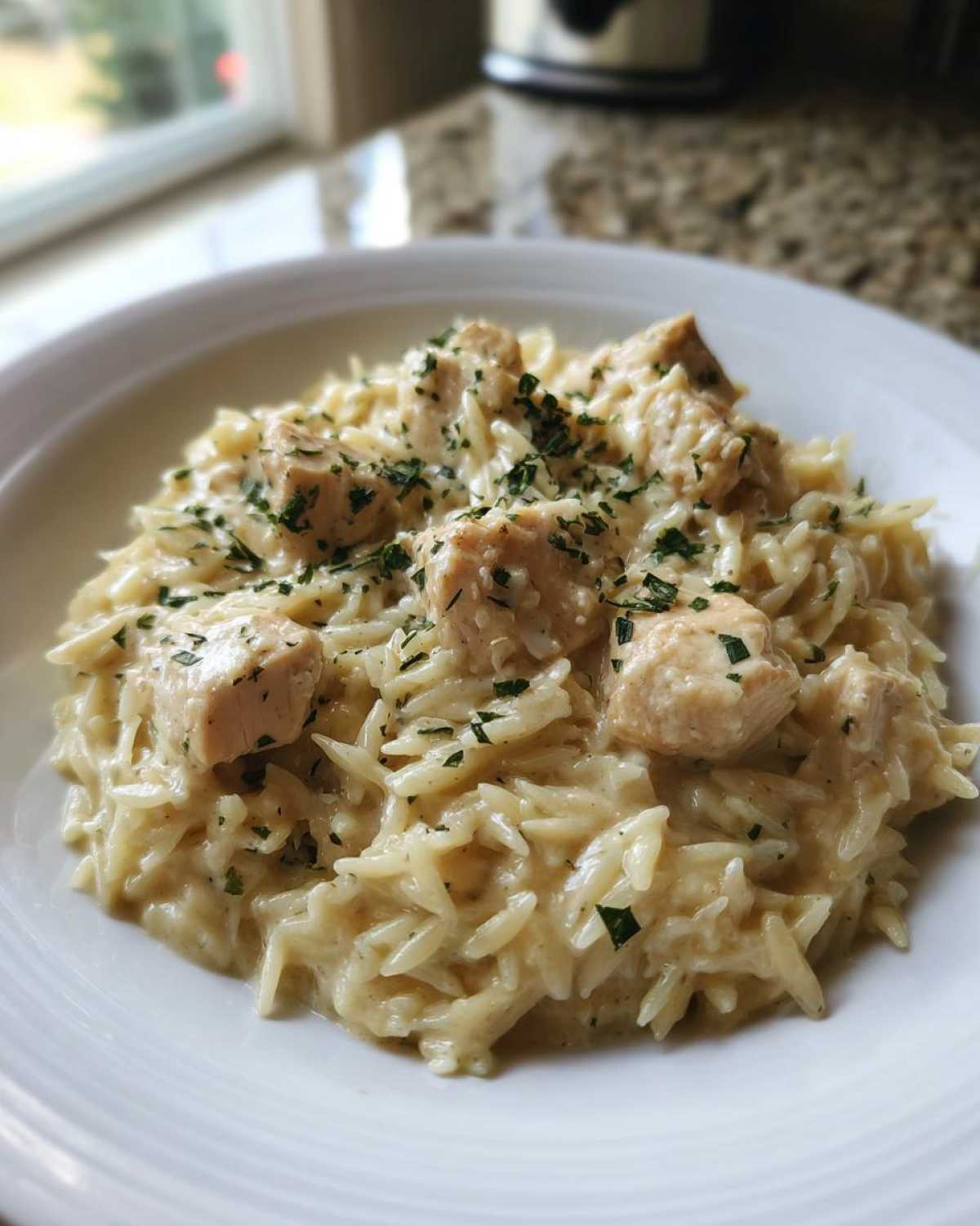 A close-up of creamy garlic parmesan orzo with chicken, garnished with parsley.