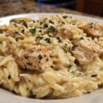 Close-up of a serving of Creamy Garlic Parmesan Orzo with Chicken topped with fresh parsley.