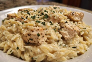 Close-up of a serving of Creamy Garlic Parmesan Orzo with Chicken topped with fresh parsley.
