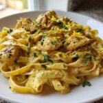 A close-up of Creamy Lemon Garlic Pasta with Chicken tossed in a rich sauce and topped with lemon zest and parsley.