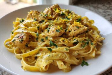 A close-up of Creamy Lemon Garlic Pasta with Chicken tossed in a rich sauce and topped with lemon zest and parsley.